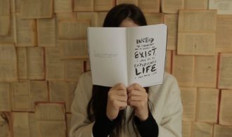 młoda kobieta zasłania twarz książką